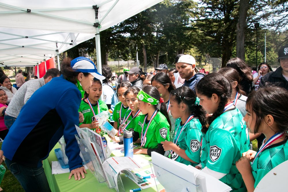 A group of young soccer players visit the a health education booth at a wellness fair