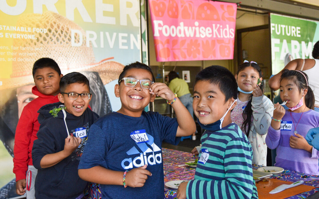 a group of smiling children show off their broccolini at the Foodwise Ferry Building Farmers Market